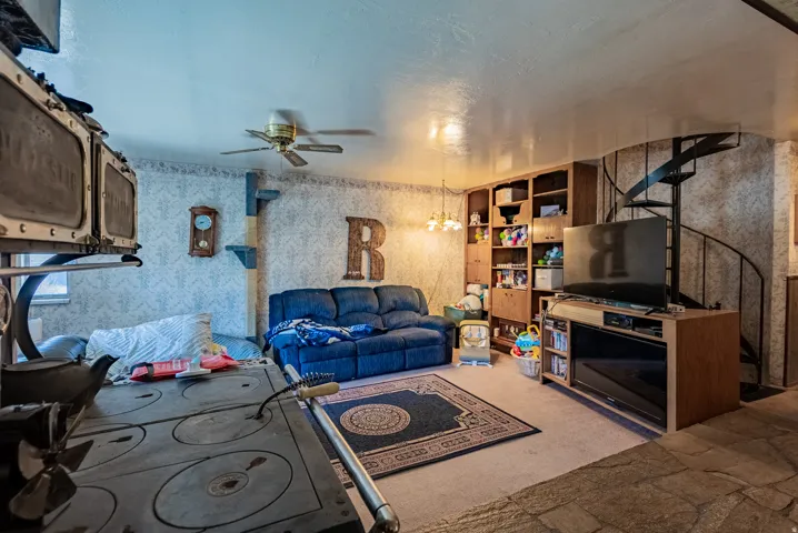 Interior space featuring an integrated spiral staircase, built-in shelving, a ceiling fan, and carpeted flooring