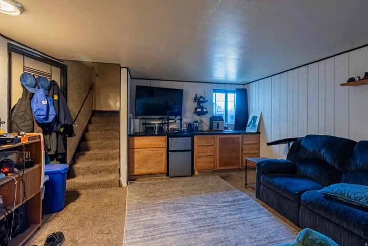 Carpeted flooring, built-in cabinetry with a dark countertop, a window with dark trim, and vertical paneling