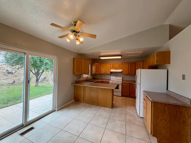 Kitchen with tile flooring, wood-finish cabinetry, a built-in kitchen island, and a sliding glass door providing access to the exterior