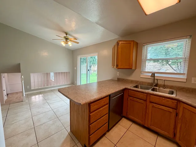 Kitchen featuring wood-finish cabinetry, stainless steel double-basin sink, and a built-in dishwasher