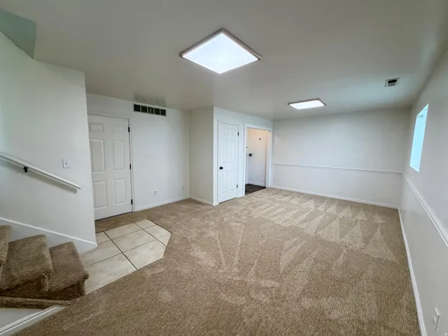 Carpeted living area featuring white panel doors, wall trim, recessed lighting, and a tile floor entryway