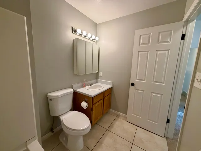 Bathroom featuring a vanity with a white countertop and wood-finish cabinetry, a wall-mounted medicine cabinet, and tile flooring