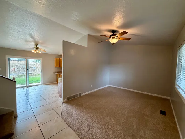 Sliding glass door, tiled flooring, carpeted area, ceiling fans, and built-in cabinetry