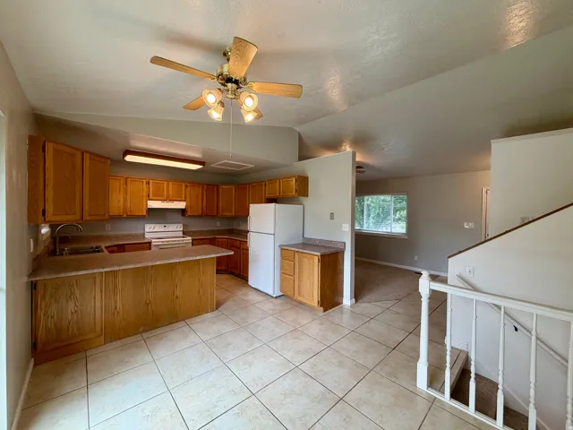 Spacious kitchen featuring a large island, wood-finish cabinetry, tile flooring, and integrated appliances
