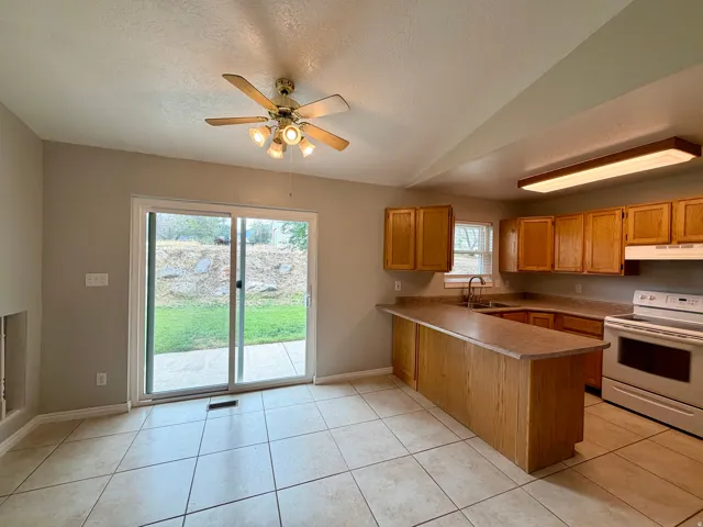 Kitchen with wood-finish cabinetry, solid surface countertops, and white appliances