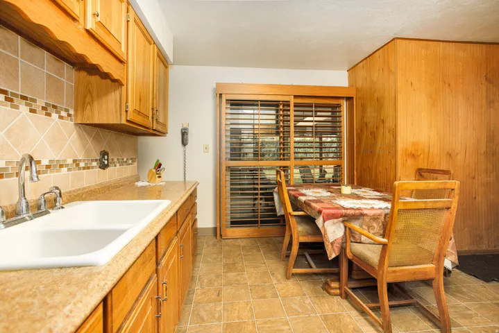 Kitchen featuring wood cabinetry, a double basin sink, tile countertops, and a decorative tile backsplash