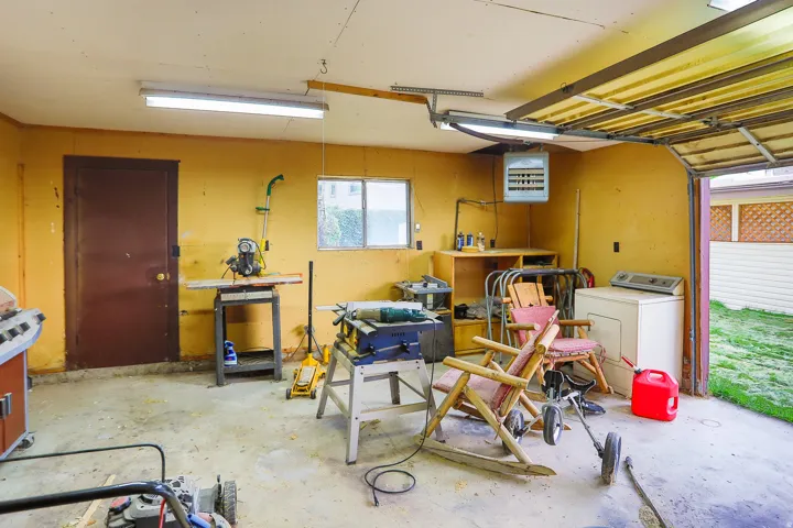 Attached garage space with a concrete floor, built-in shelving, two fluorescent light fixtures, and a small window