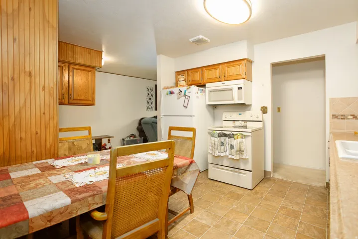 Kitchen area featuring wood cabinetry, white appliances, and a tile backsplash