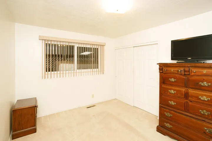 Carpeted flooring, white walls, horizontal window blinds, and sliding closet doors