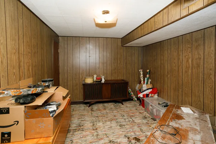Wood-panel walls with a drop ceiling and overhead lighting