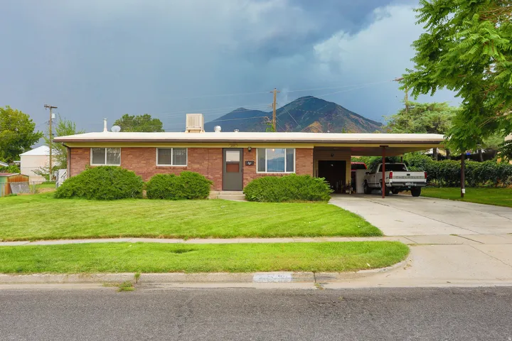 Brick exterior with a flat roofline, integrated carport, and an established lawn