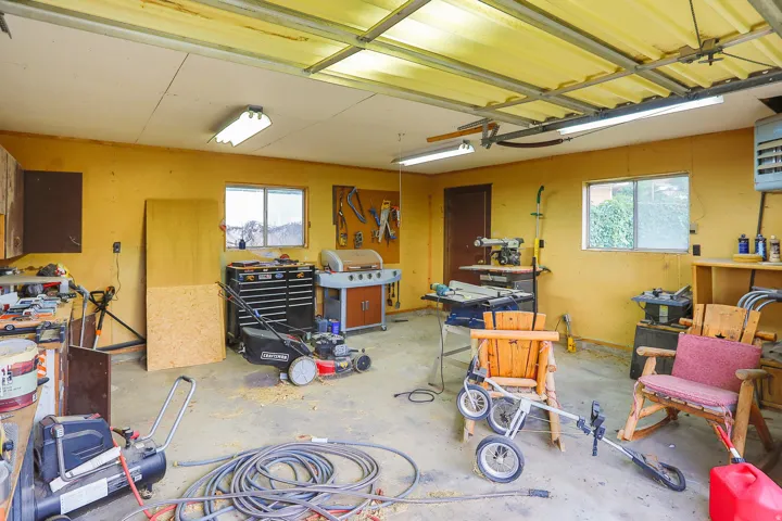 Concrete flooring with multiple windows, fluorescent lighting, and a roll-up garage door