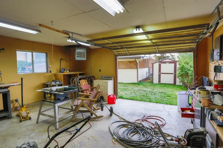 Garage space with an overhead door, fluorescent lighting, and a rear window