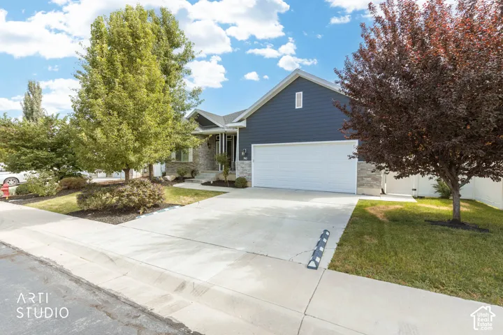 Two-car garage with a concrete driveway, blue horizontal siding, and stone accents