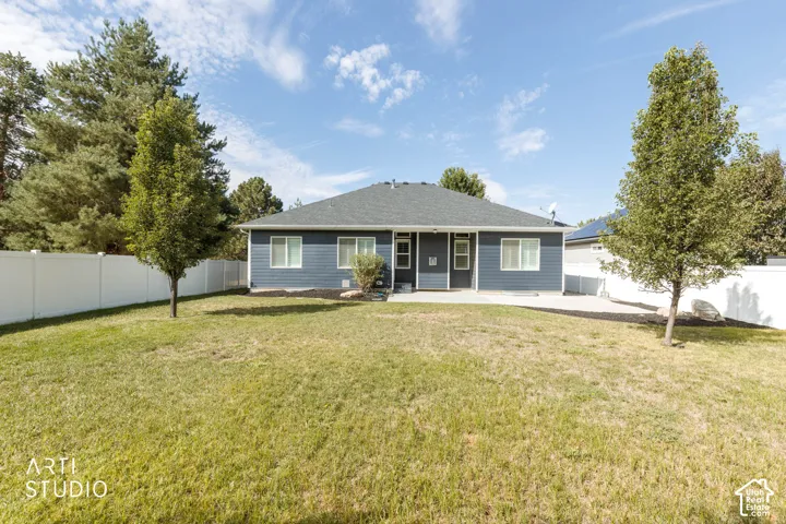 Expansive lawn area, mature trees, white privacy fencing, and a concrete patio