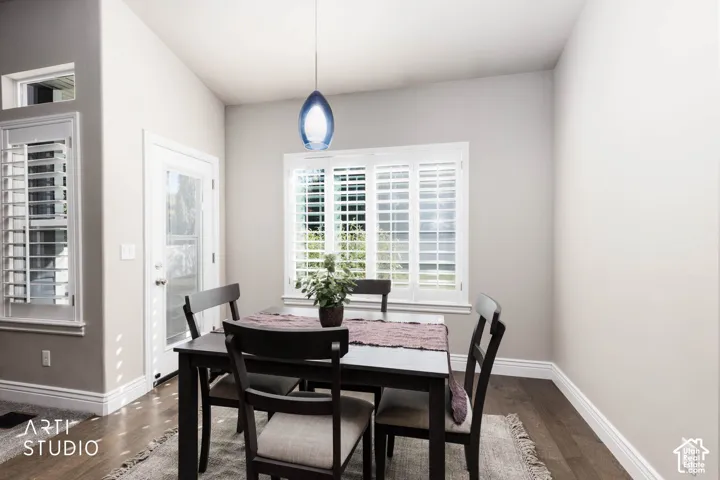 Dining area with wood-finish flooring, plantation shutters, and a glass-paneled door