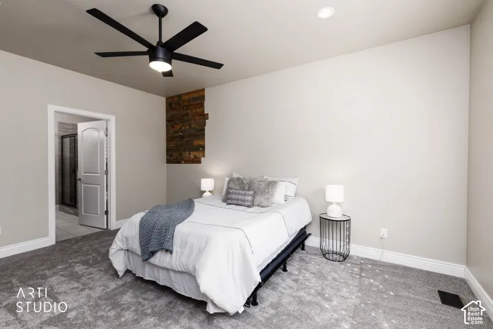 Grey carpet flooring, recessed ceiling lighting, a contemporary black ceiling fan with integrated lighting, a wood-finish accent wall, and a white interior door