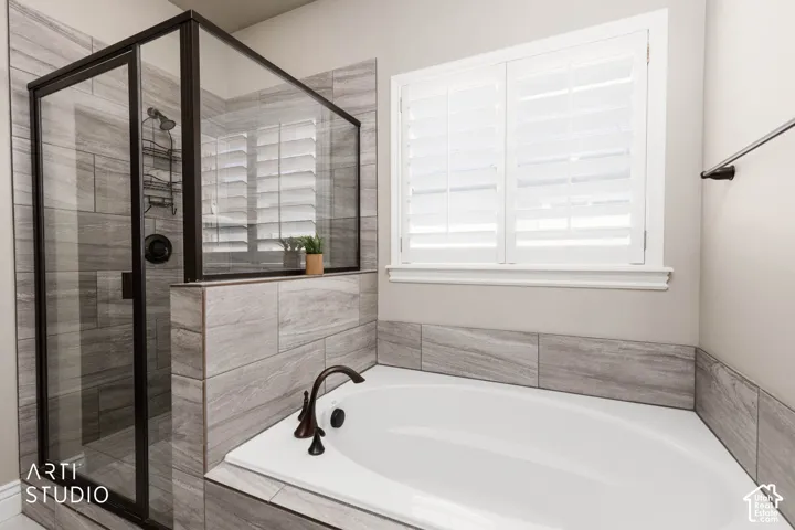 Built-in soaking tub with bronze-finish fixtures, tile surround, and a separate glass-enclosed shower with a bronze-finish showerhead
