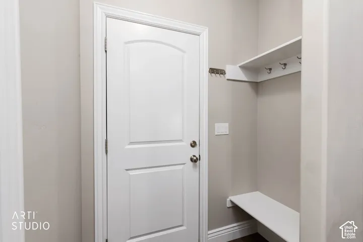 Built-in mudroom bench with shelving and coat hooks, paneled door with polished chrome hardware, and neutral wall paint