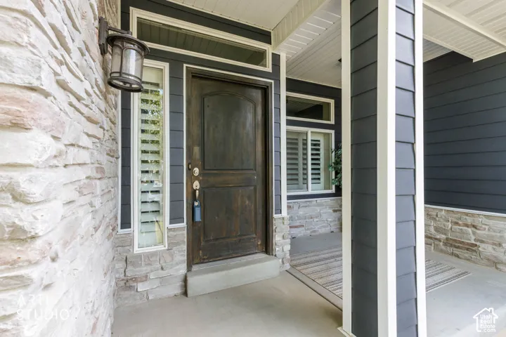 Stone veneer exterior with dark wood entry door, sidelight windows, and decorative wall lantern