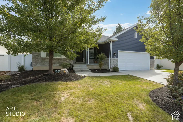 Exterior featuring horizontal siding, stone veneer accents, an attached garage, a concrete driveway, and established trees