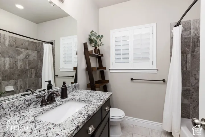 Bathroom featuring a vanity with a granite-style countertop, an undermount sink, and a framed mirror