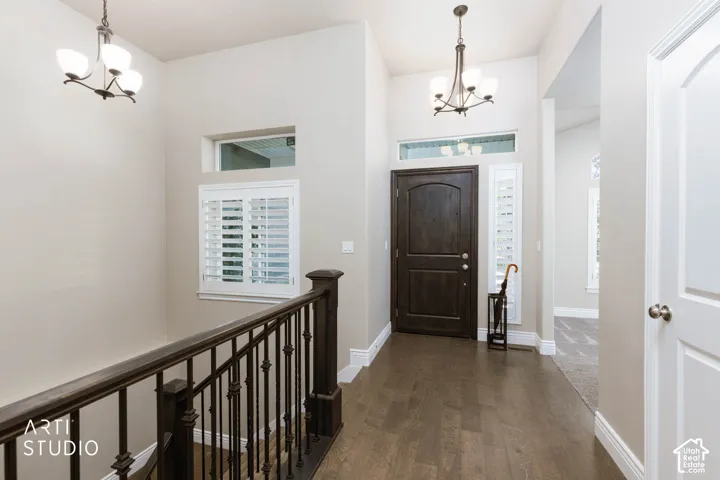 Entryway featuring a dark wood door, wood-finish flooring, and a chandelier