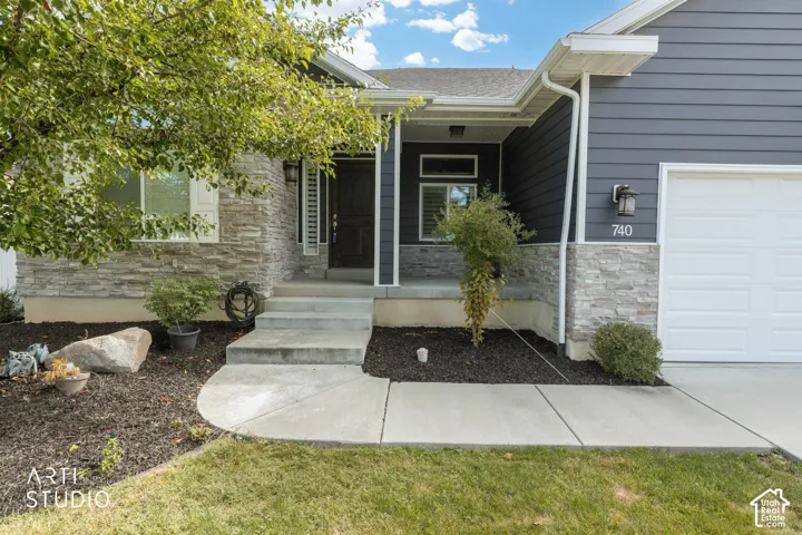 Exterior featuring horizontal siding, stone veneer accents, a covered entry, a paneled garage door, and a concrete walkway