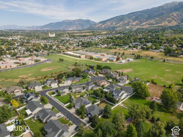 Aerial perspective of a residential community with abundant green spaces, mountain backdrop, and multiple single-family homes