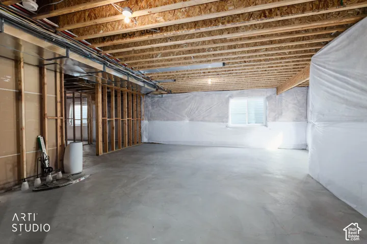 Unfinished basement with exposed ceiling joists, concrete flooring, and framed interior walls