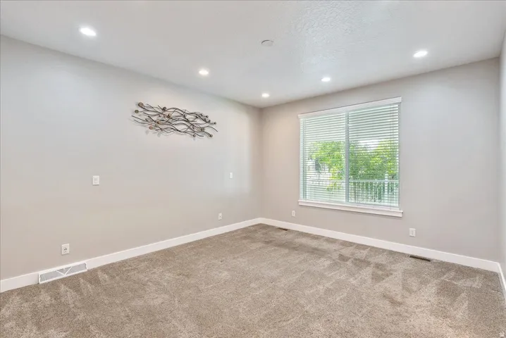 Recessed ceiling lighting, light gray wall paint, white trim, window with blinds, and neutral carpet flooring