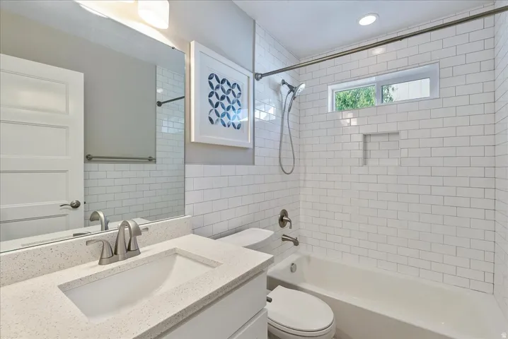 Bathroom featuring a built-in tub with a subway tile surround, recessed lighting, and a window for natural light