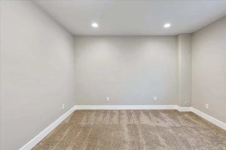 Recessed ceiling lighting illuminates light gray walls and plush carpet flooring