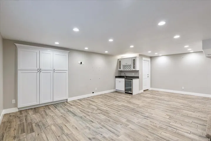 Recessed lighting throughout, tile-finish flooring, built-in white cabinetry, wet bar, and beverage refrigerator