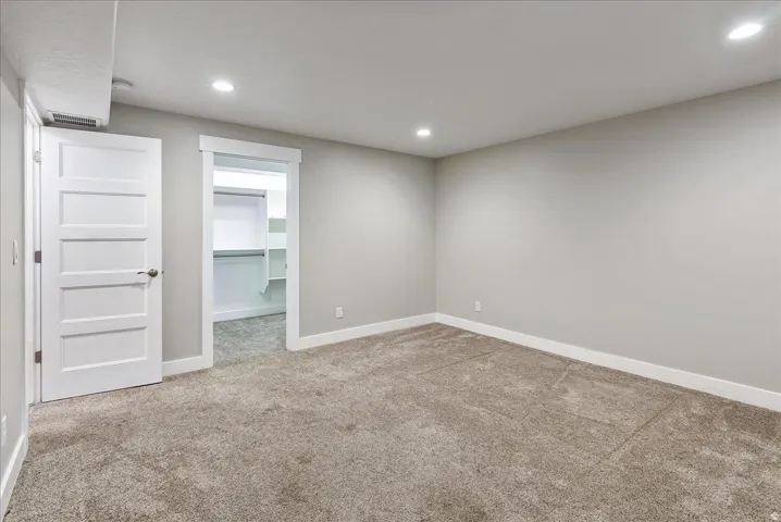 Neutral tone wall paint, recessed lighting, carpeted flooring, built-in closet shelving, and a flat panel interior door