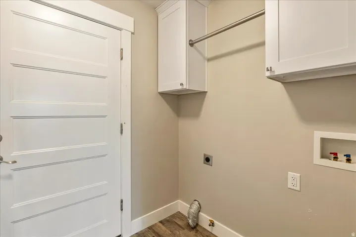 Dedicated laundry room featuring white cabinetry with chrome hardware, a wall-mounted rod for hanging garments, tile-finish flooring, and built-in shelving for storage and organization