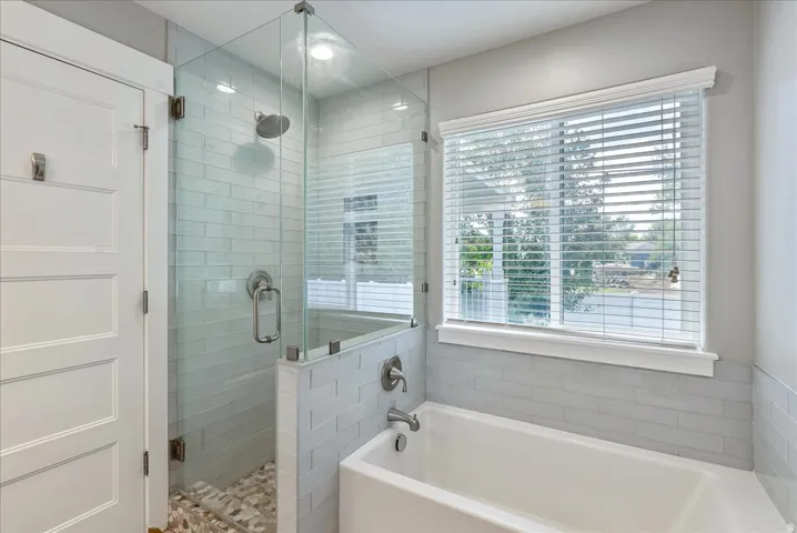 Spa-inspired primary bathroom featuring a frameless glass walk-in shower enclosure with subway tile surround