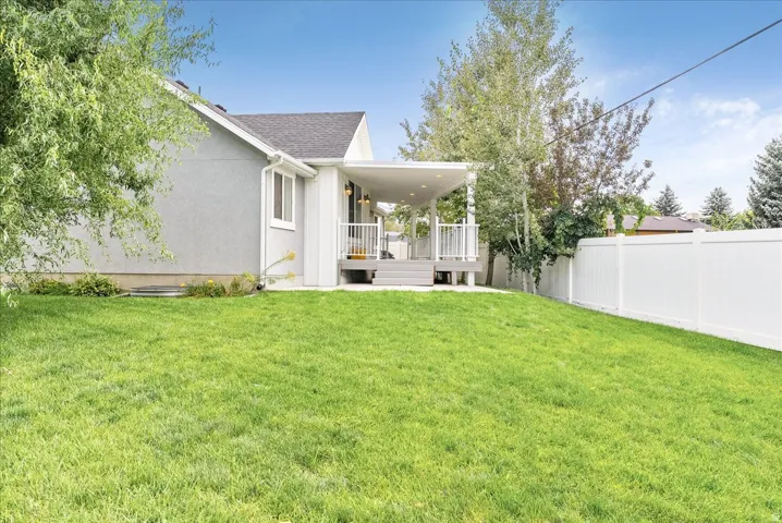 Expansive manicured lawn with mature landscaping and established trees, bordered by a white vinyl fence