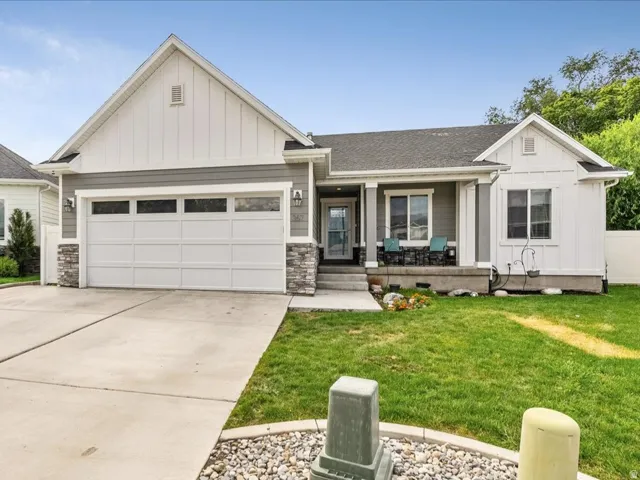Curb appeal featuring a covered porch, stone accent siding, a two-car garage, and a concrete driveway
