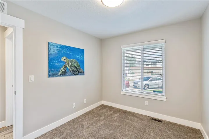 Neutral wall finish, window with horizontal blinds, and carpeting