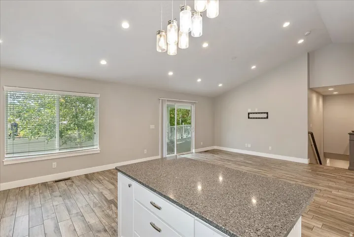 Spacious open-concept room featuring vaulted ceilings, recessed lighting, and tile-finish flooring
