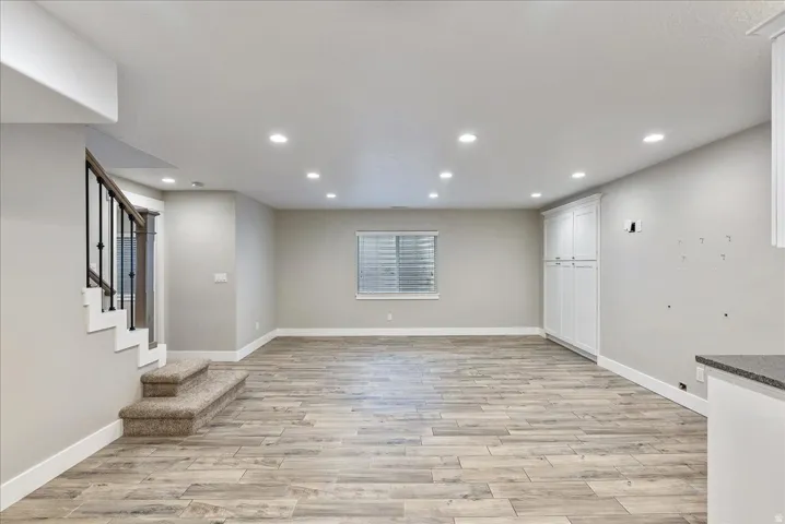 Spacious room featuring recessed lighting, wood-finish flooring, a built-in cabinet, and a window with blinds