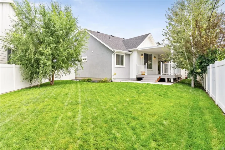 Expansive lawn with mature trees and white vinyl fencing