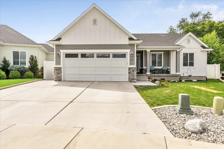 Modern craftsman-style residence featuring a two-car garage, stone facade accents, and a covered front porch
