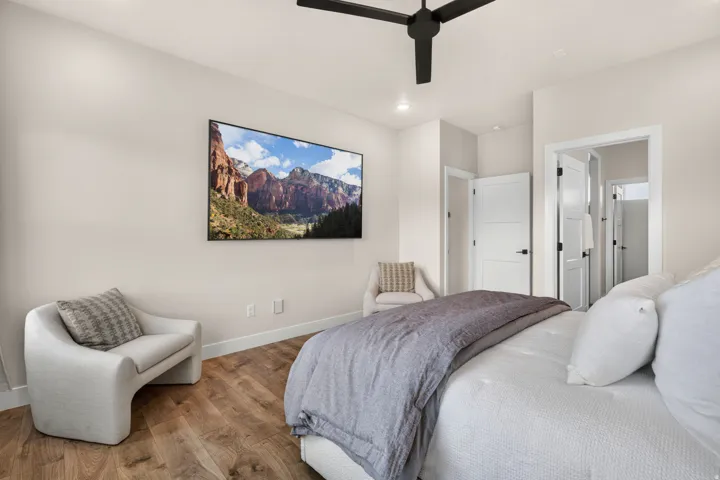 Wood-finish flooring, white walls, and a black ceiling fan