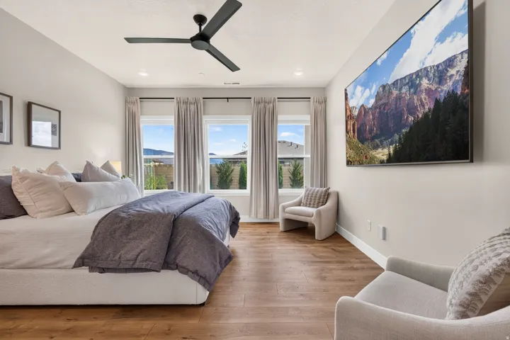 Vaulted ceiling with a matte black ceiling fan, recessed lighting, wood-finish flooring, and multiple windows with drapery rods