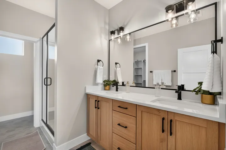 Dual vanity with light wood-finish cabinetry, white countertops, and matte black hardware