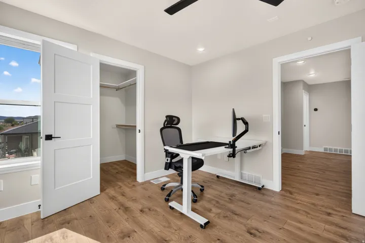 Wood-finish flooring, recessed lighting, ceiling fan, window with exterior scenery, and a built-in closet with shelving and hanging rod