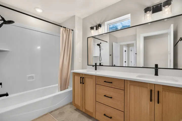 Dual vanity with light wood-finish cabinetry, white countertop, and matte black fixtures