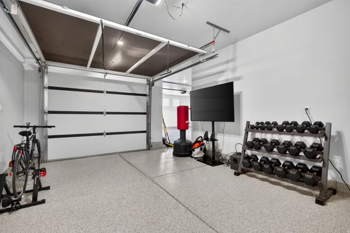 Garage featuring an overhead door, high ceilings, and light-toned walls